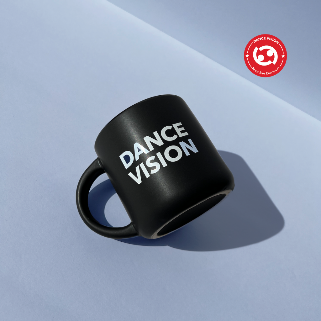 Stoneware 14 oz. mug. Matte black outside and glossy black color inside with Dance Vision wordmark and Dance Vision logo in white. Microwave safe. Front view.
