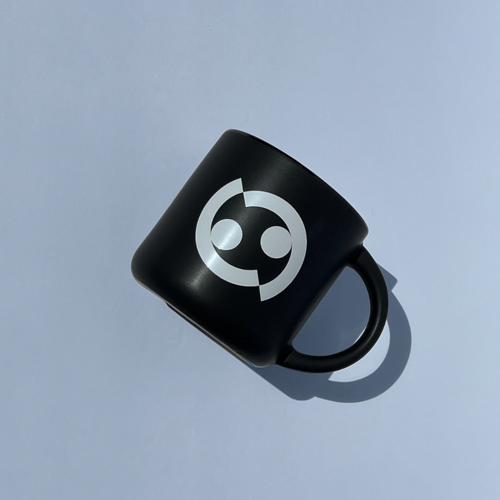 Stoneware 14 oz. mug. Matte black outside and glossy black color inside with Dance Vision wordmark and Dance Vision logo in white. Microwave safe. Back view.